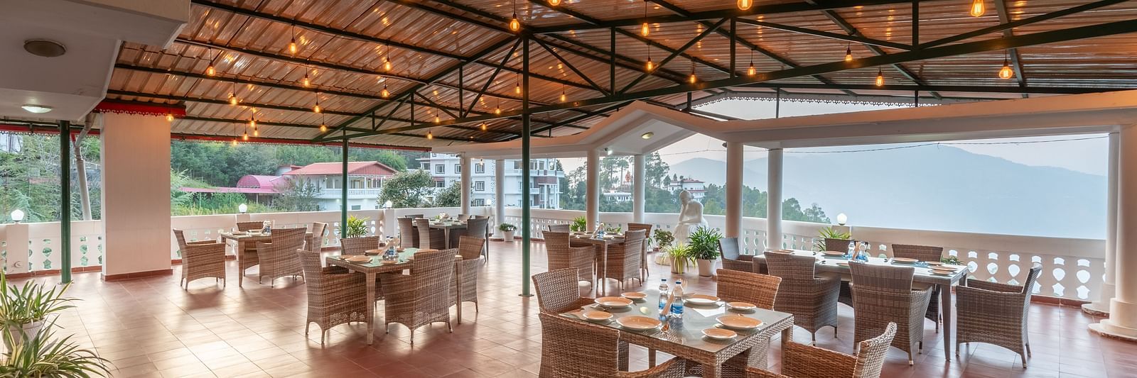 Covered terrace at DLS Tehri Club Resort with tables and chairs, perfect for enjoying the views.